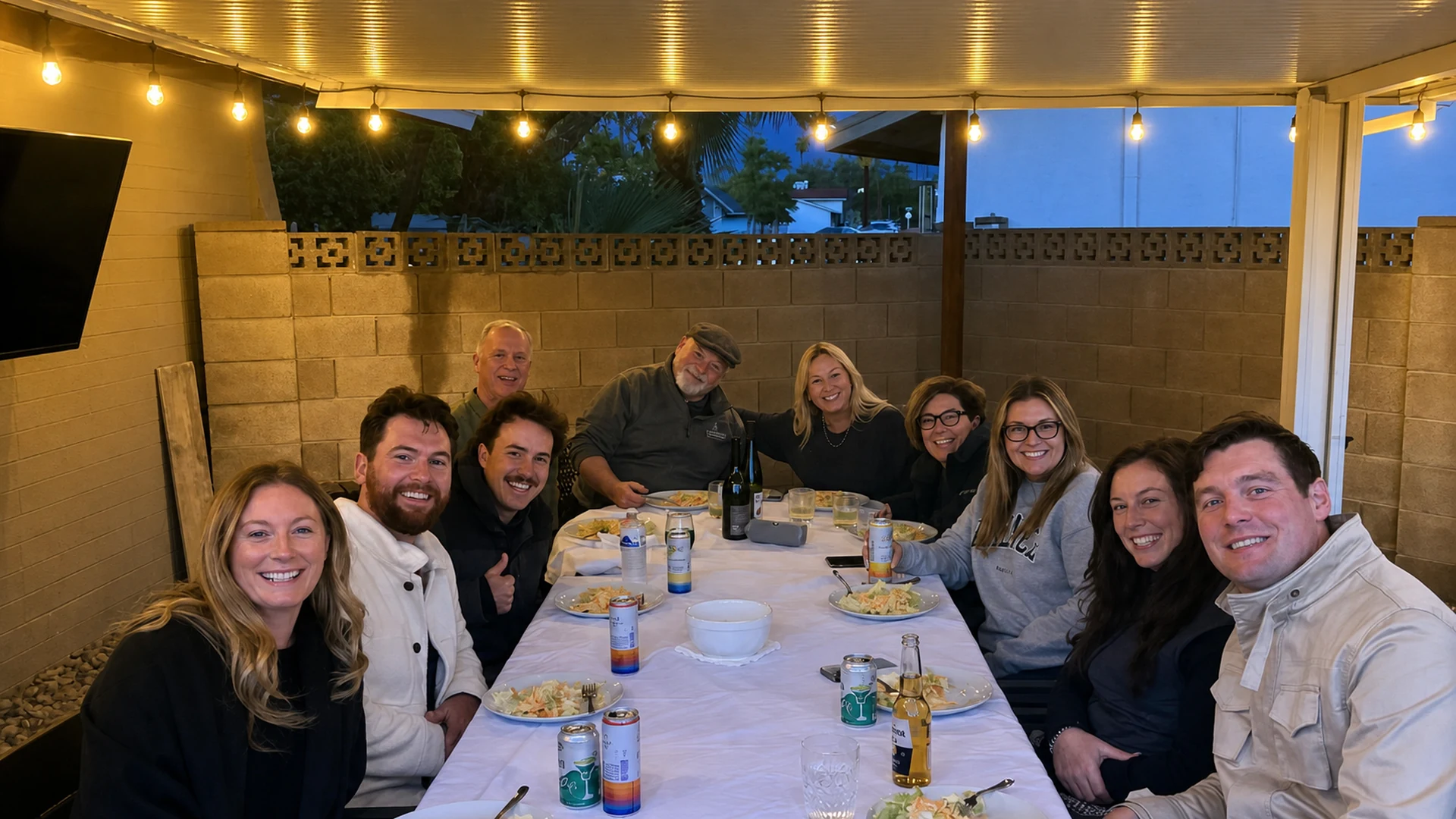 Private group smiling around a hibachi dinner table under patio string lights