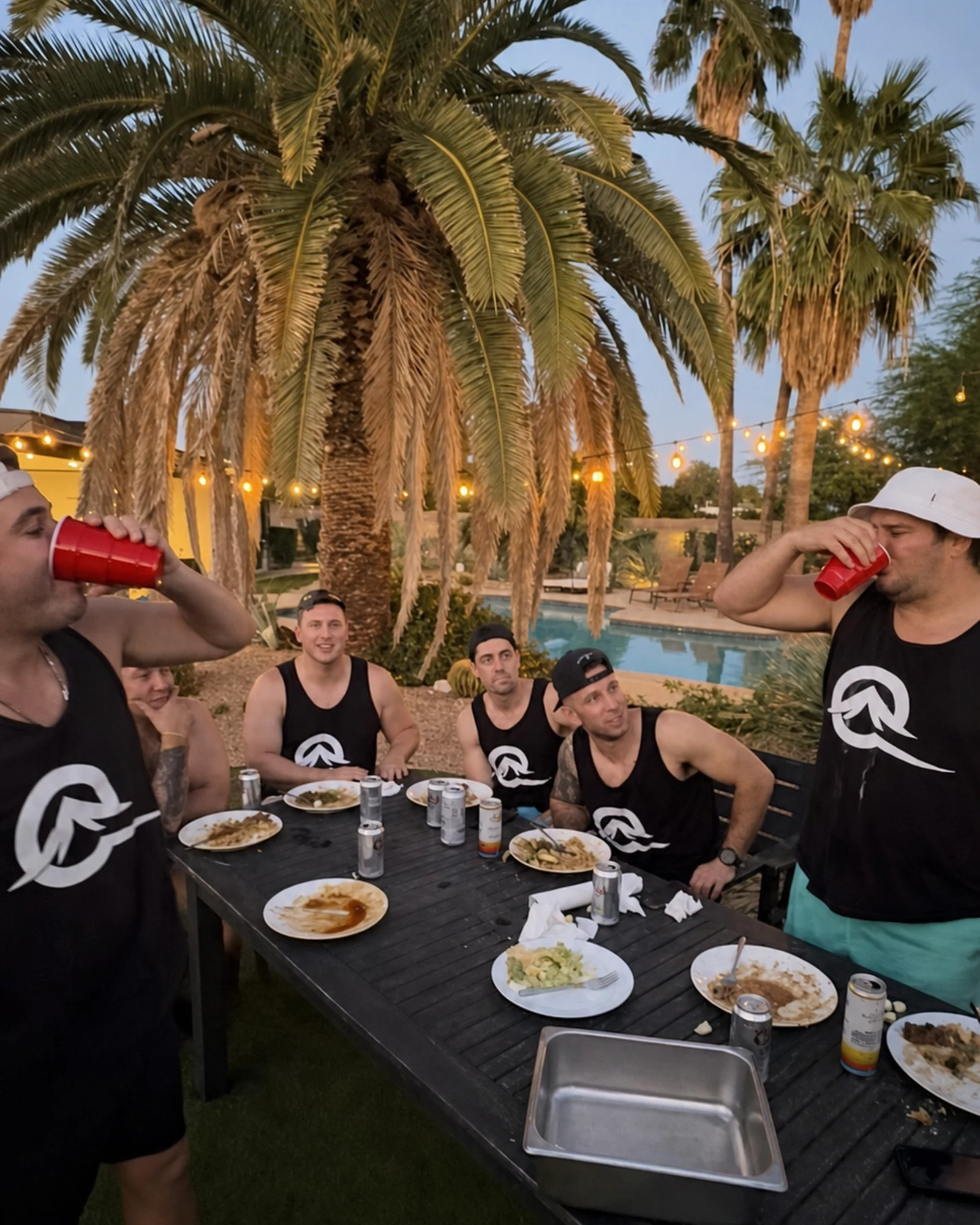 Friends celebrating around a poolside hibachi table beneath palm trees