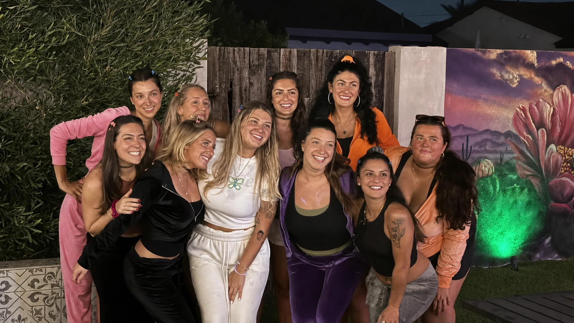 Women posing together beside a colorful desert mural