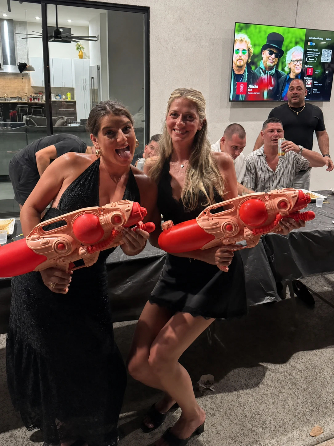 Women posing with red water guns during a hibachi party