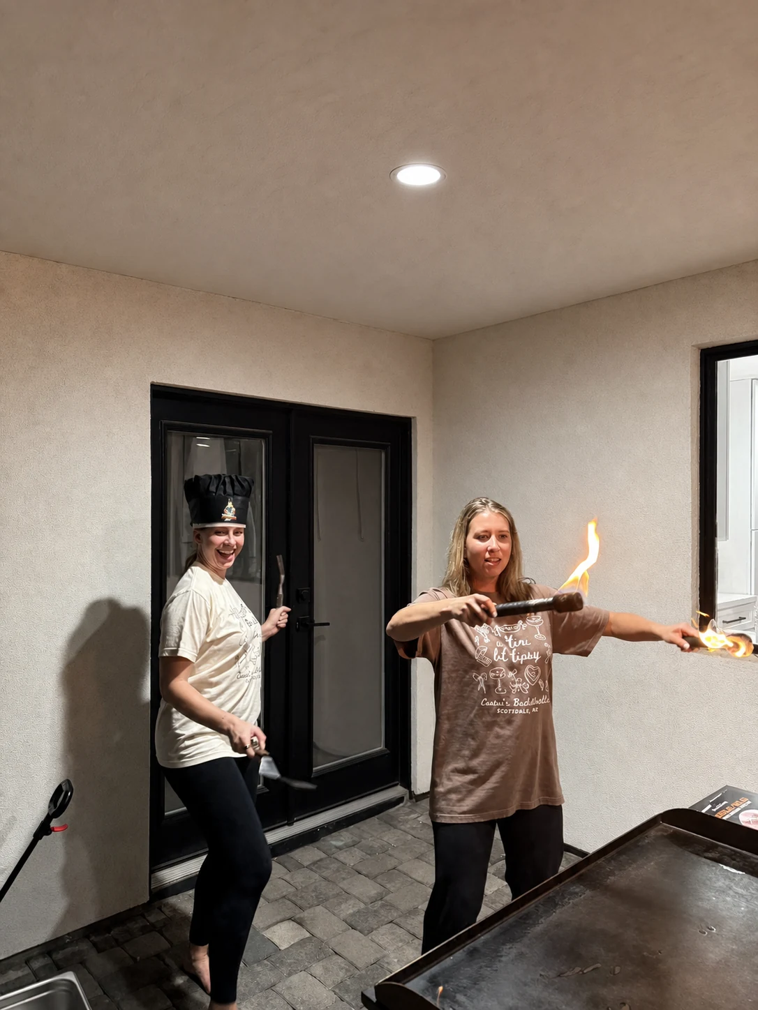 Women posing with flaming hibachi utensils during a party