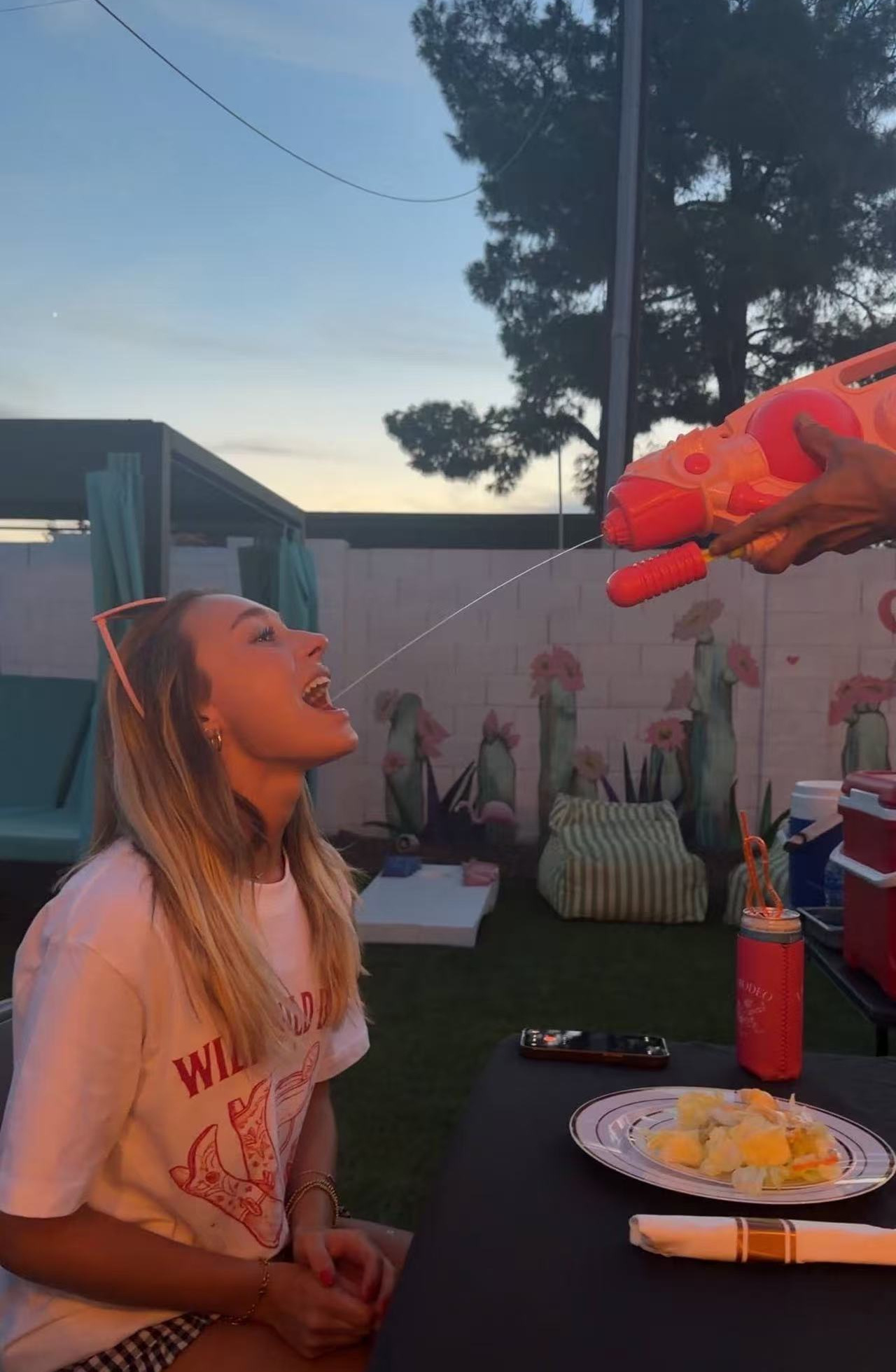 Guest enjoying sake served from a water gun at an outdoor hibachi party